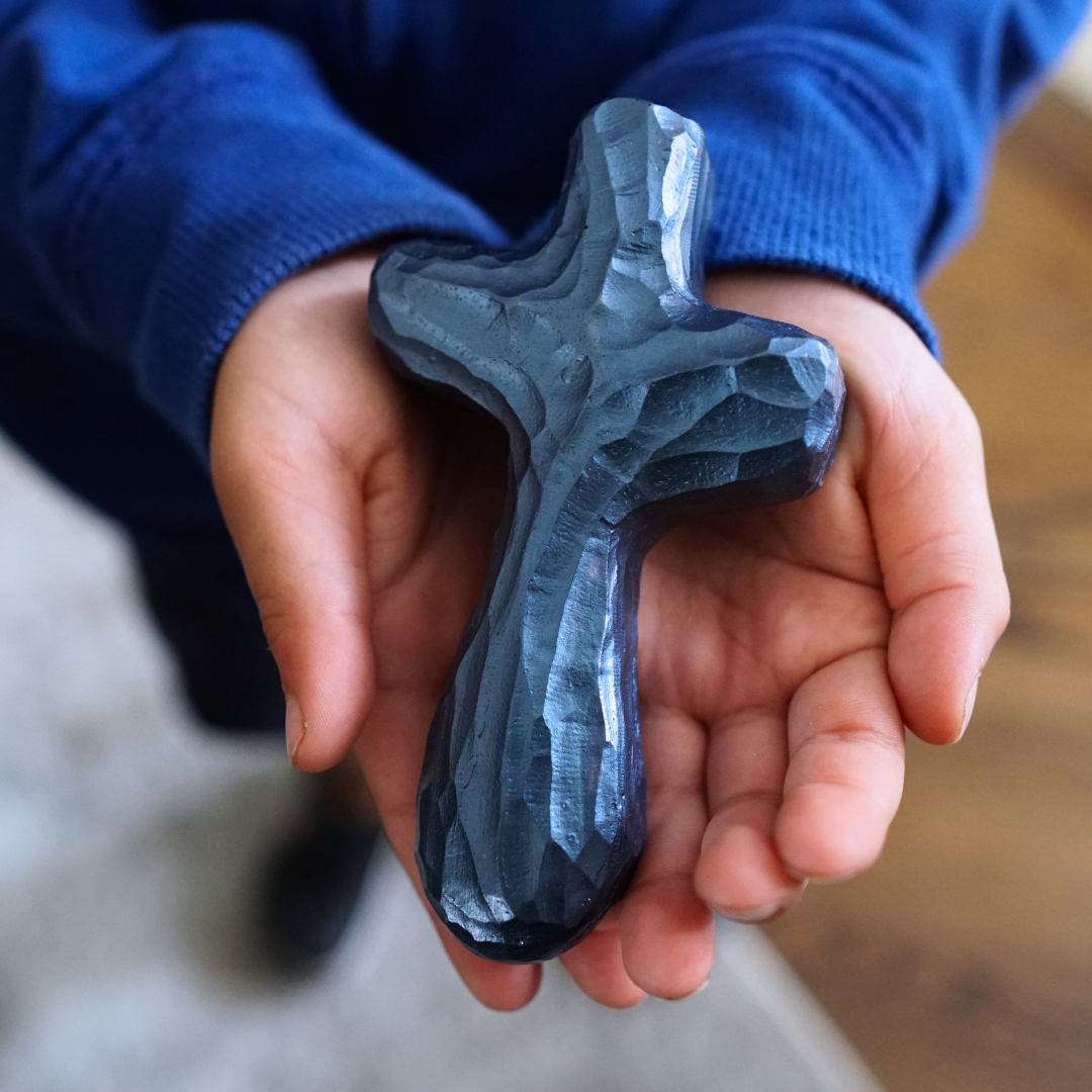 Child's hands holding blue painted holding cross