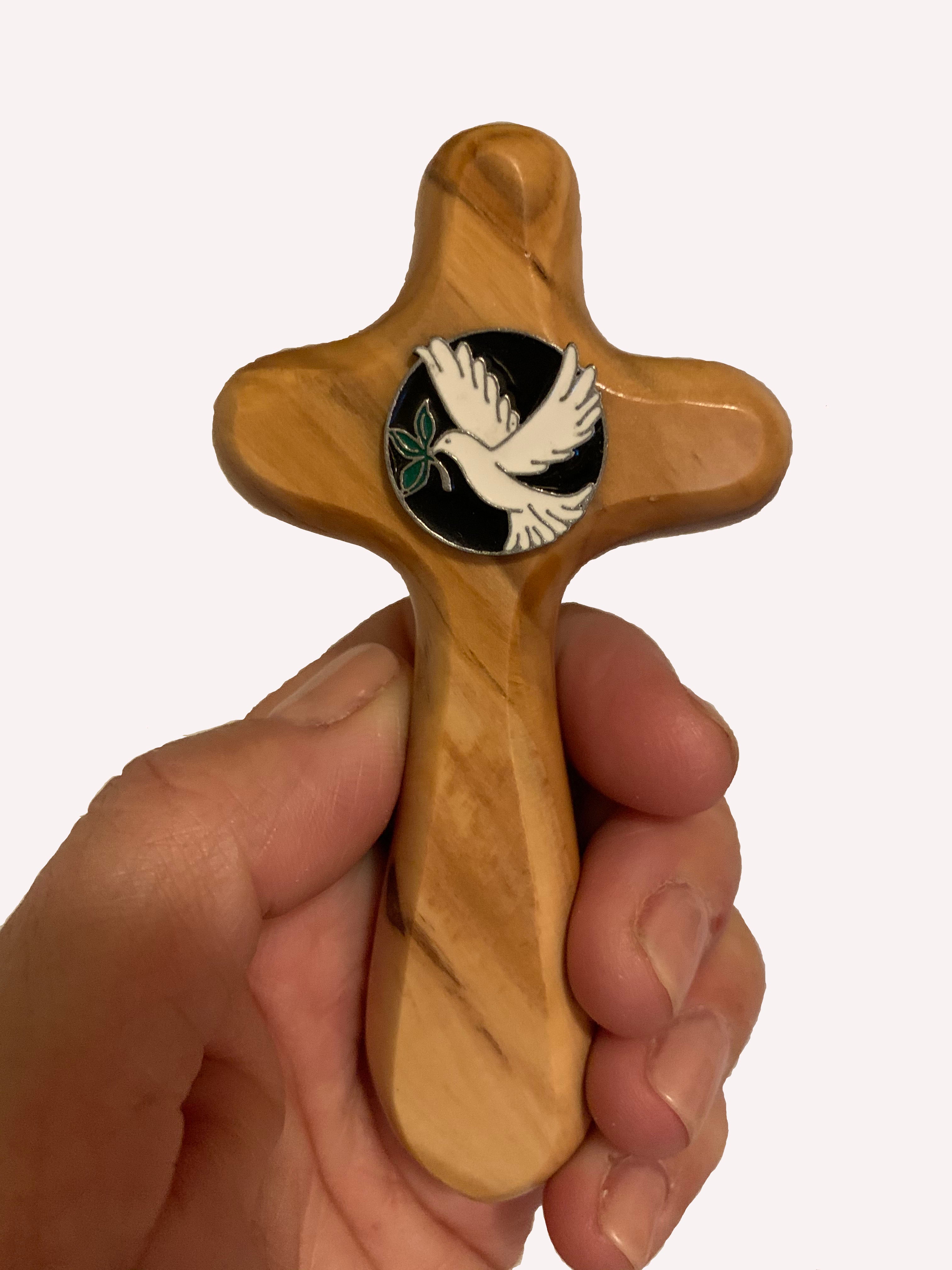 Hand holding olive wood holding cross with Holy Spirit dove medallion
