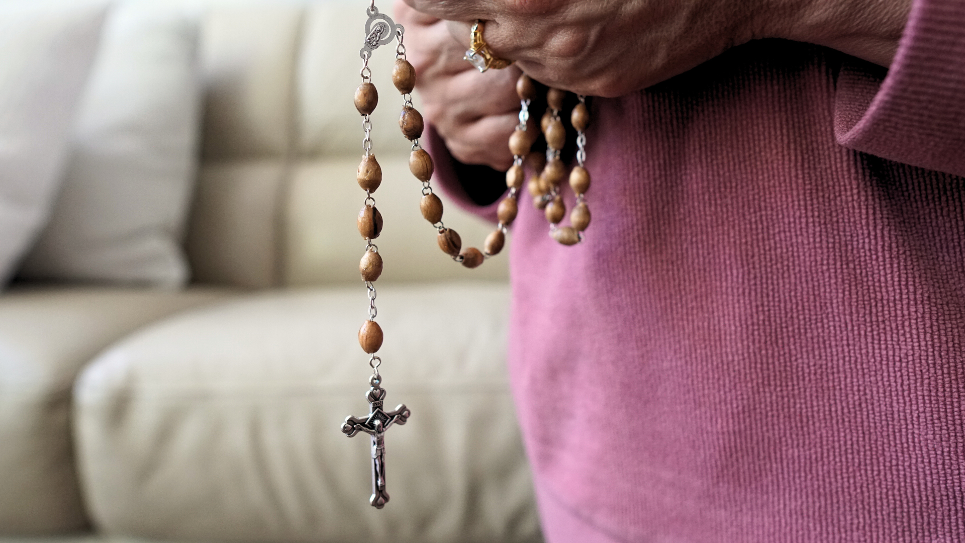 Woman praying rosary with Olive Wood rosary
