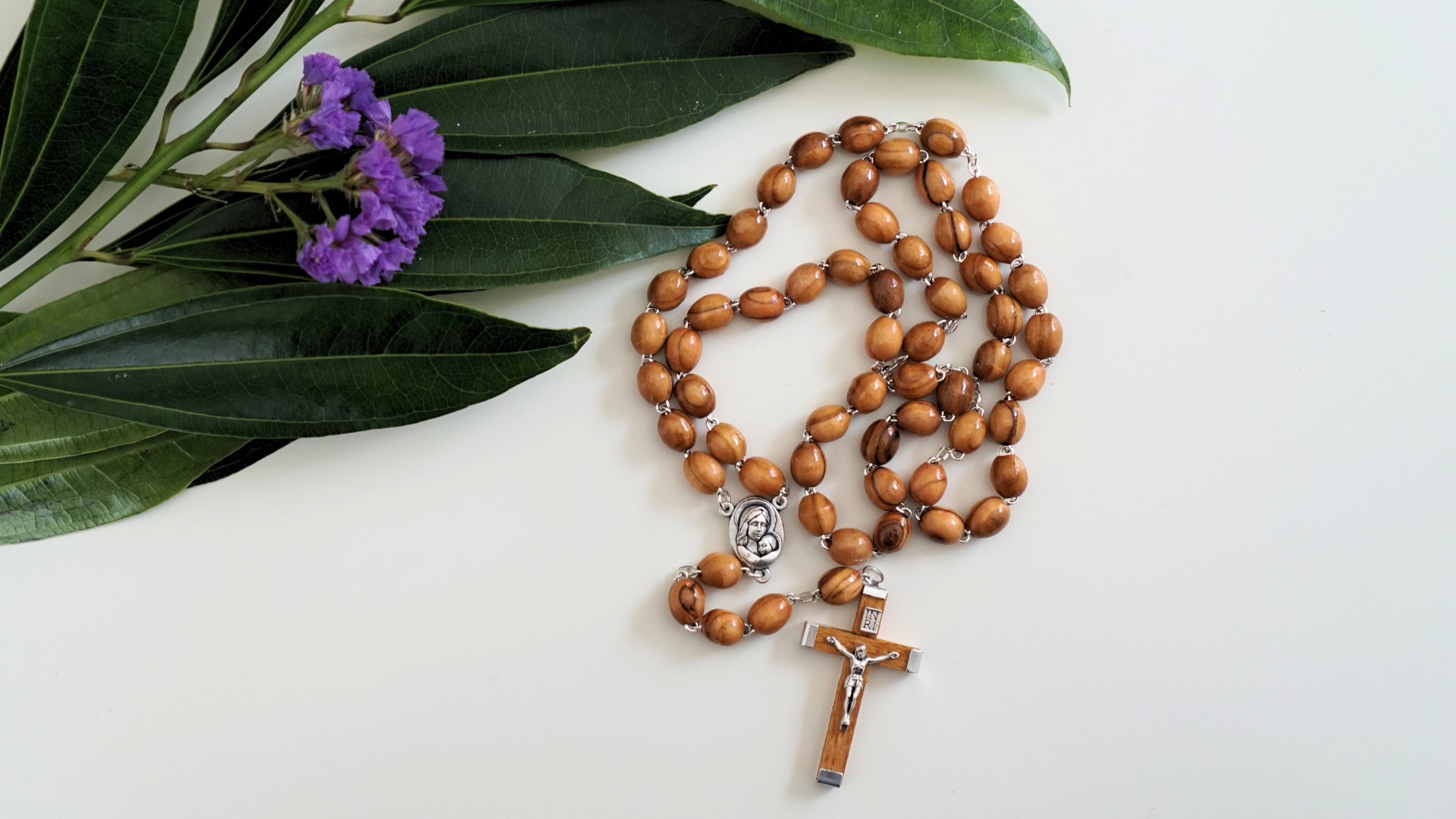 Olive wood rosary next to flowers and leaves